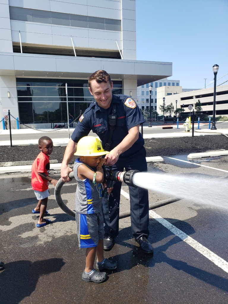 Child with firehose and fireman
